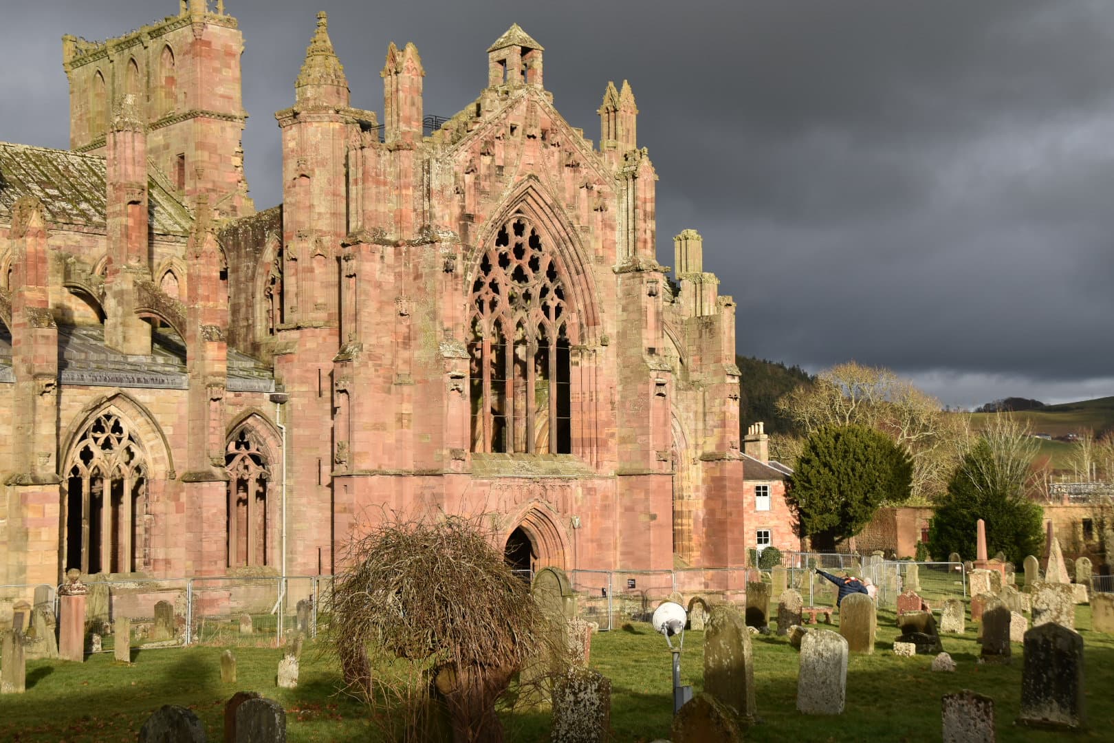 Soaring Gothic arches and red sandstone masonry of ruined Melrose Abbey.