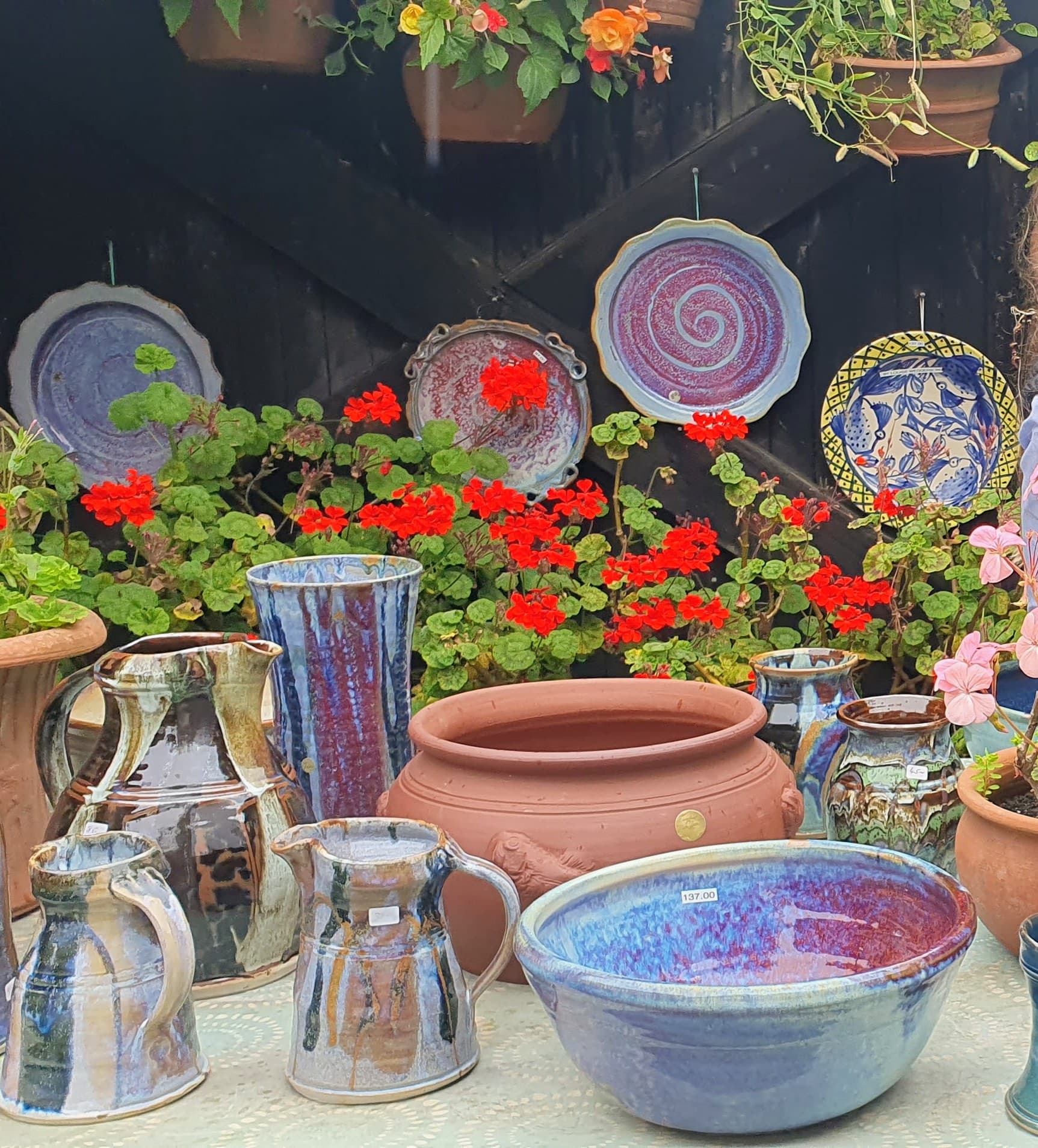 Handcrafted terracotta and glazed stoneware pottery displayed in the stone courtyard at Crail Pottery in Fife
