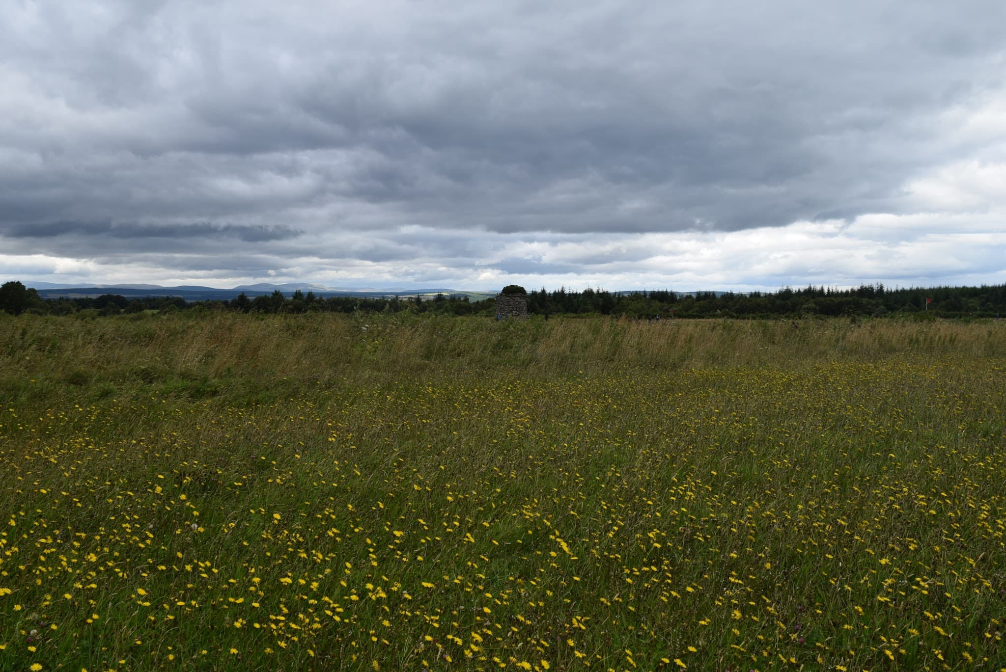 Open moorland, memorial cairn and flags at Culloden Battlefield.
