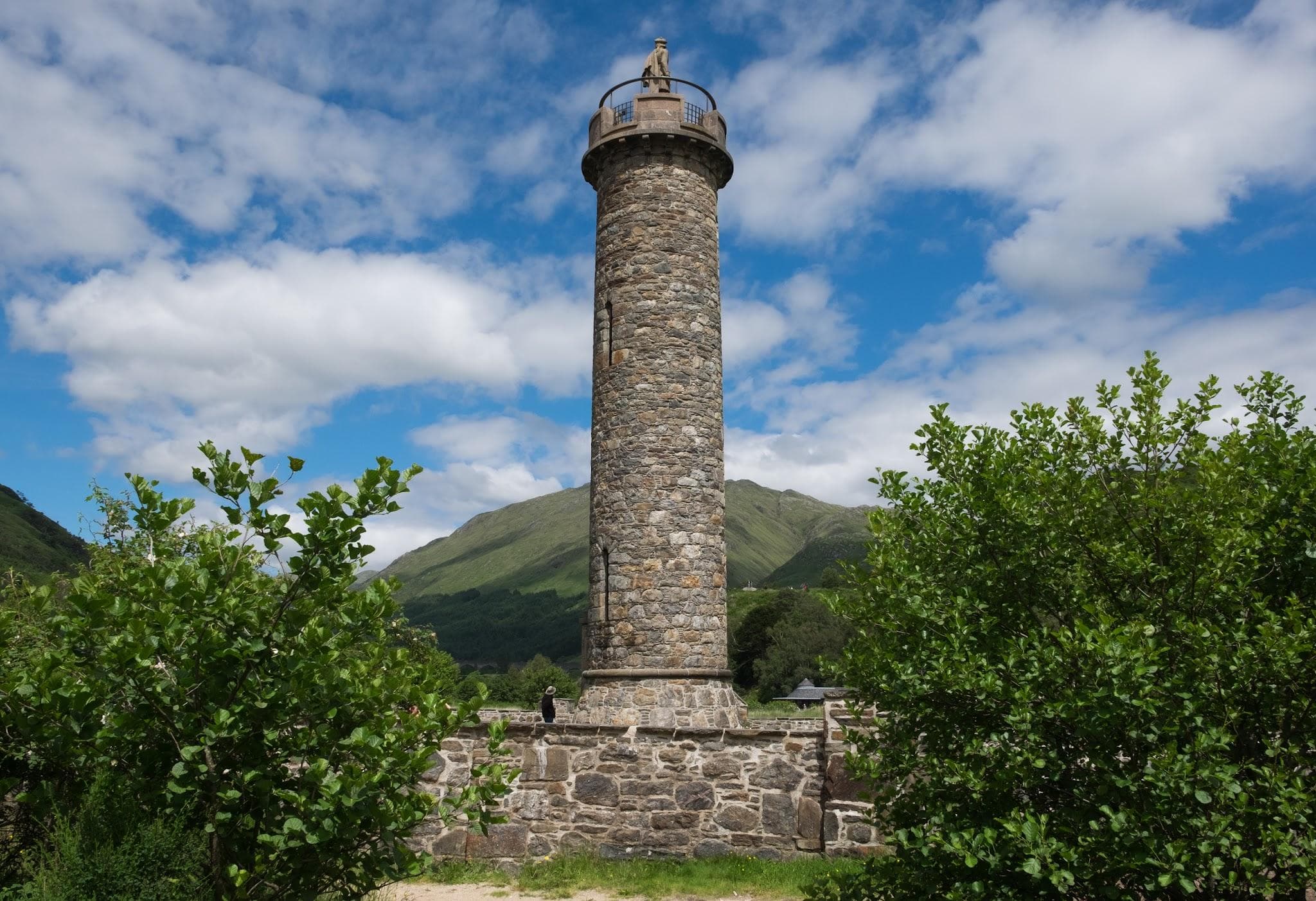 Glenfinnan Monument standing at the head of Loch Shiel surrounded by mountains.