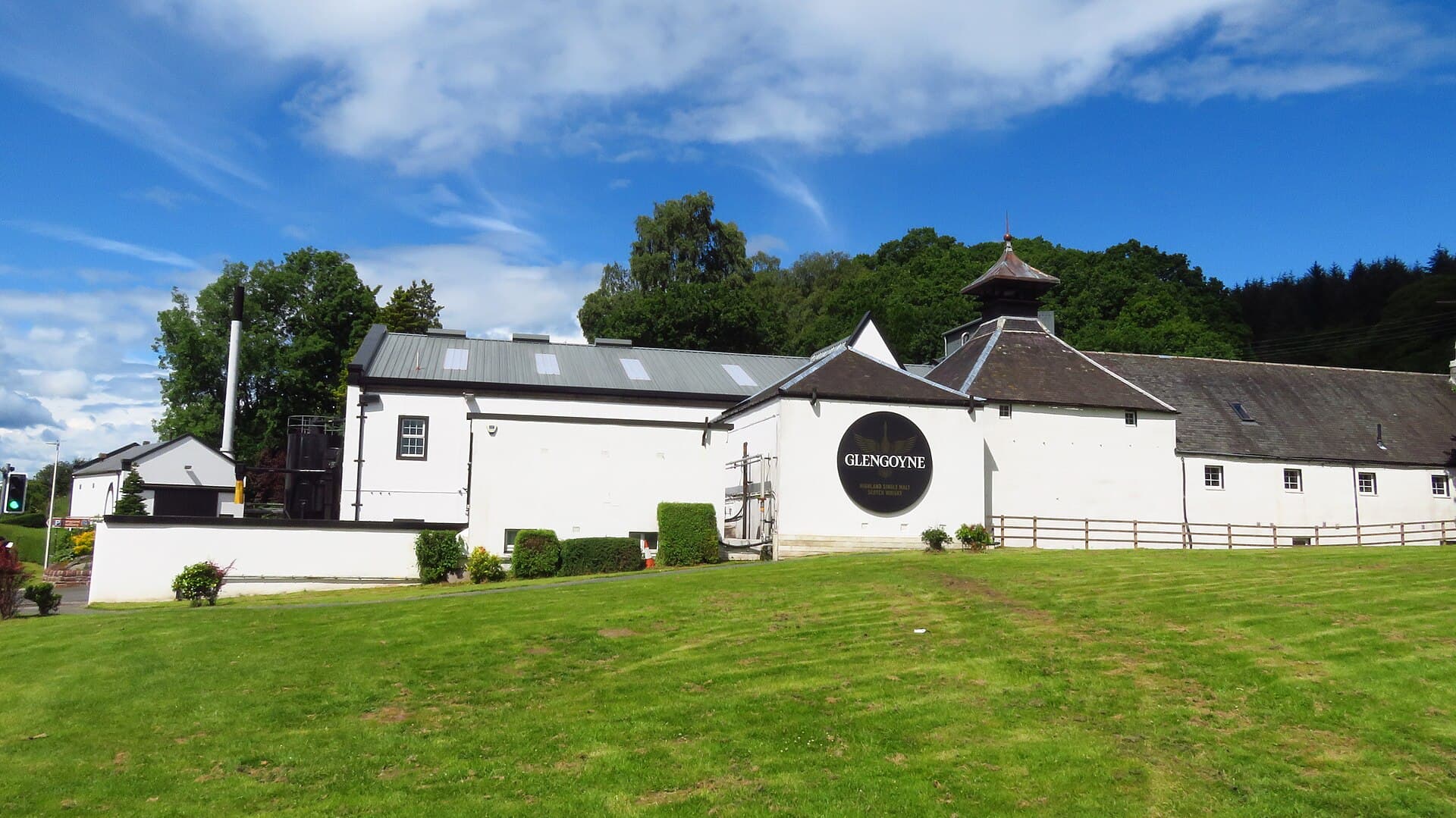 Whitewashed distillery buildings of Glengoyne with pagoda kilns beneath the steep green slopes of Dumgoyne