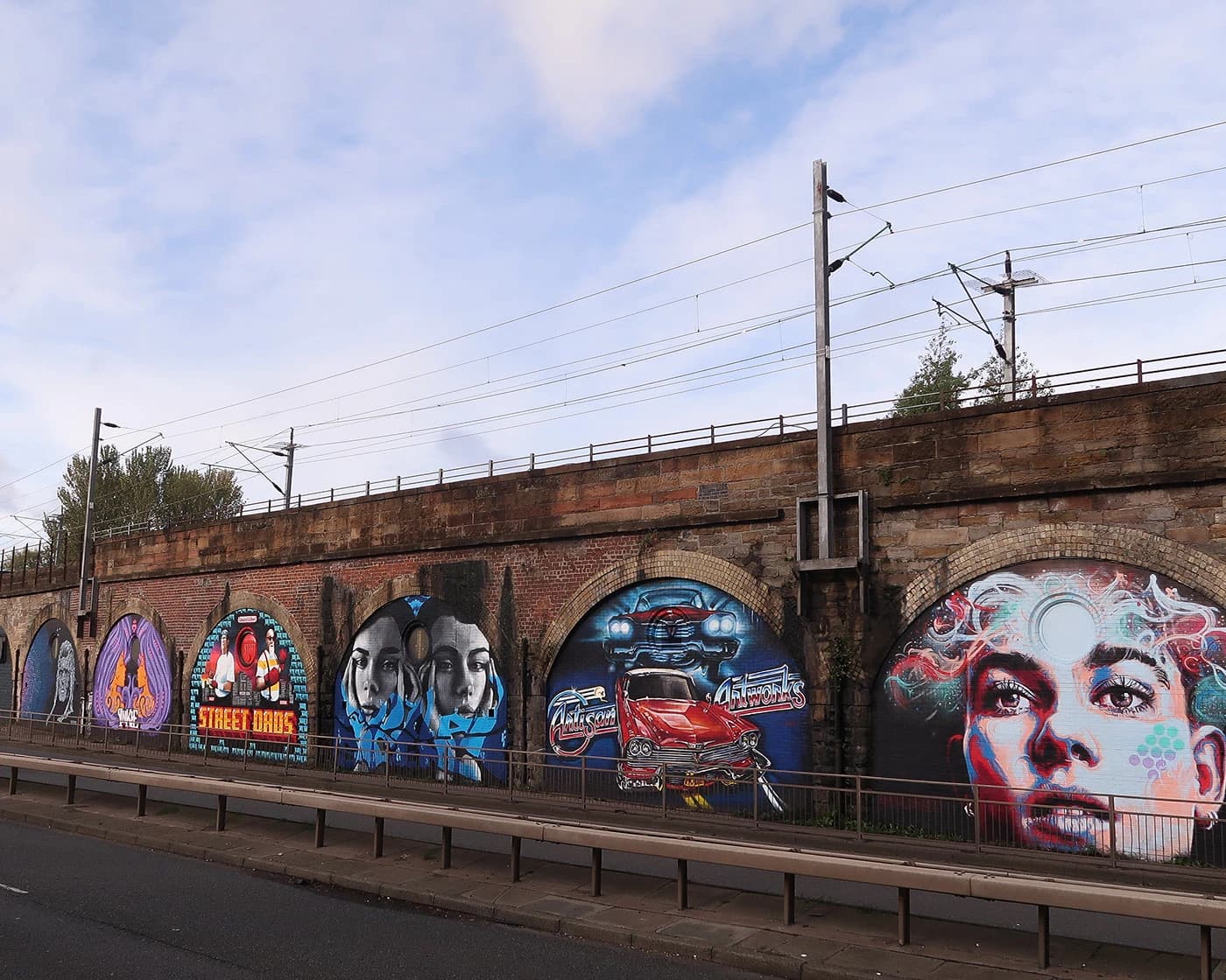 Colourful street-art murals painted across a row of railway arches at SWG3 in Glasgow.