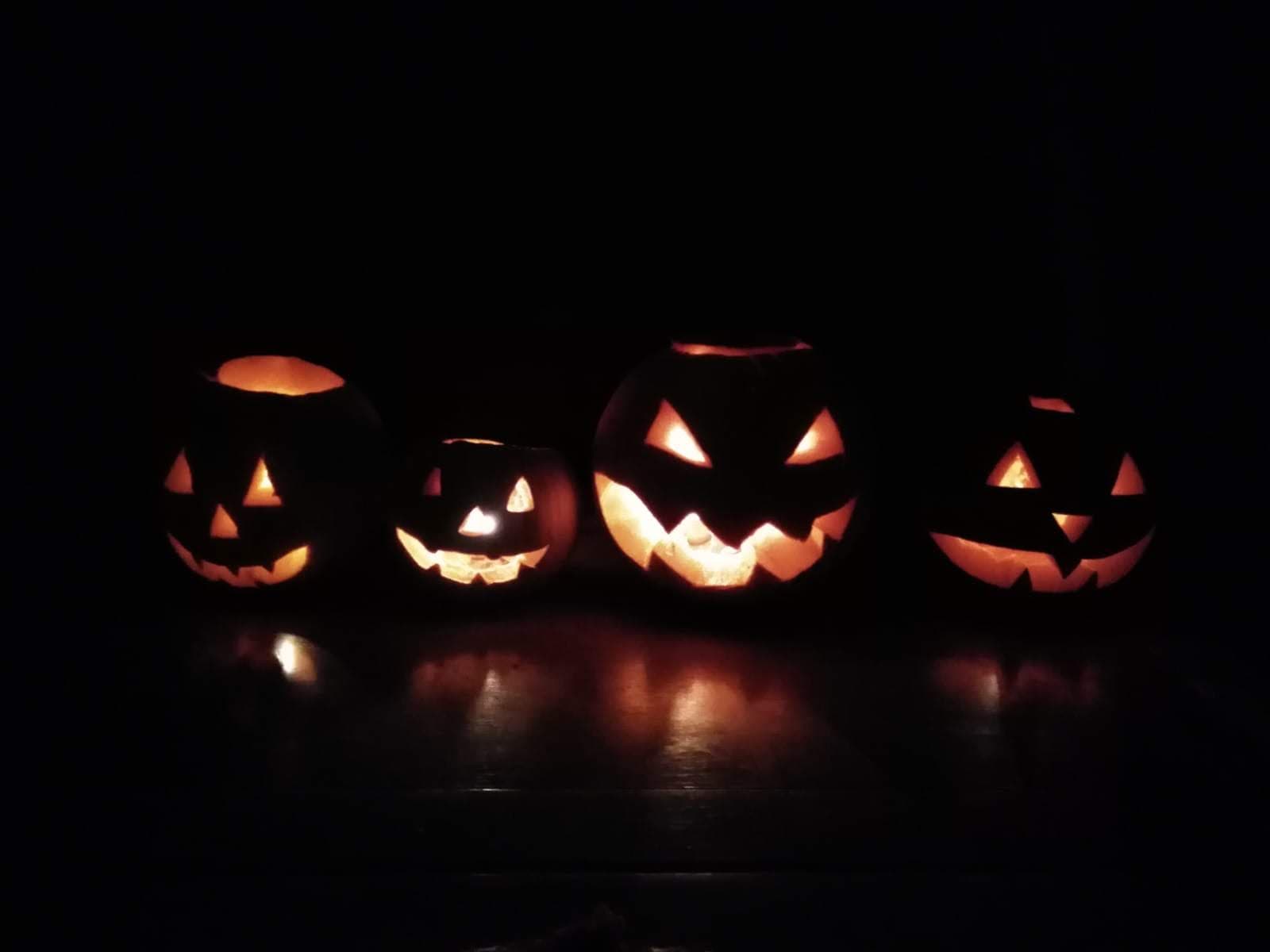 Carved Halloween lanterns glowing outside in the dark.