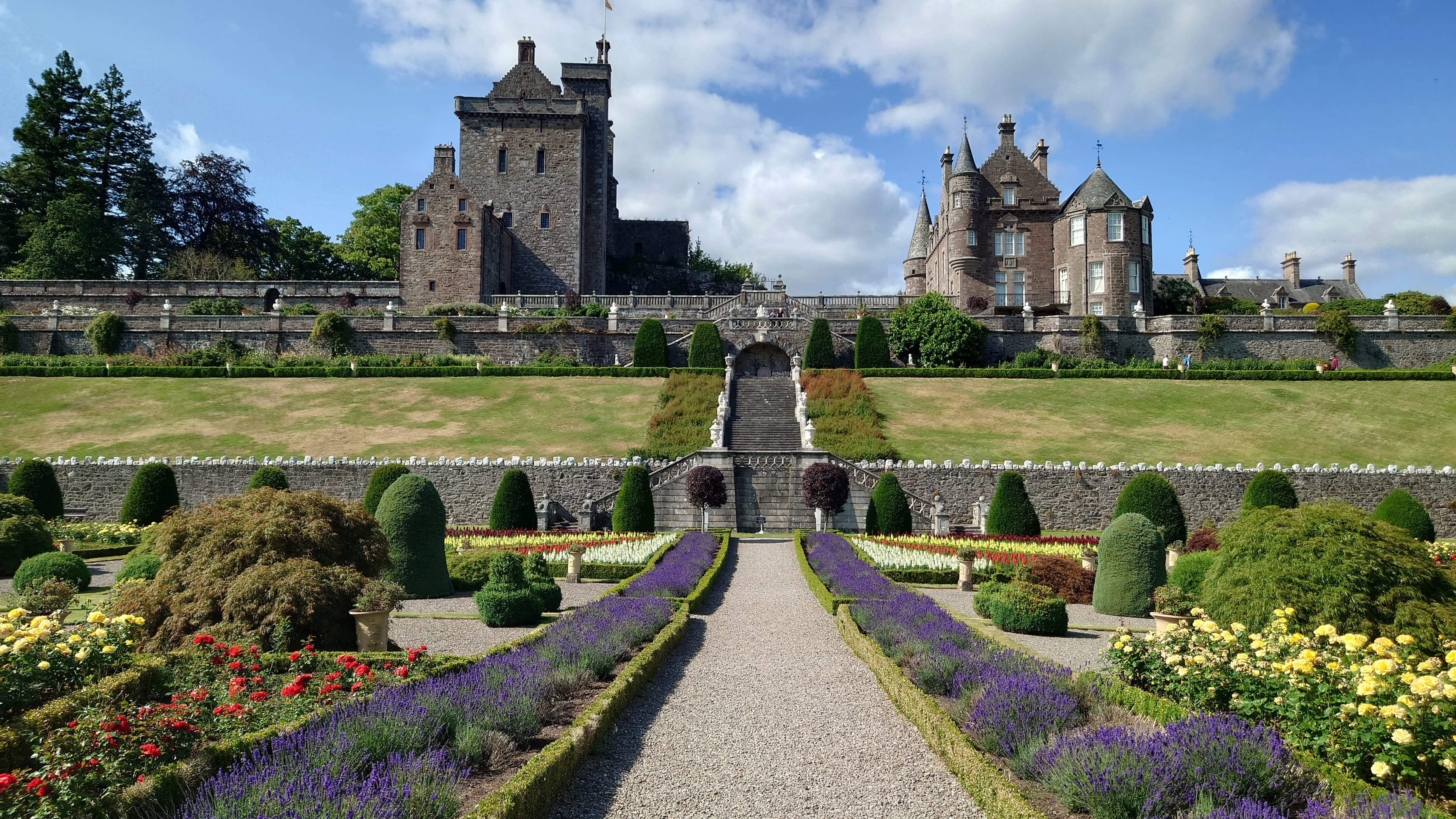The formal terraces and central path of Drummond Castle Gardens, with the castle buildings above.